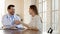 Smiling doctor and young woman shaking hands at meeting