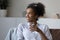 Smiling dreamy African American woman holding glass of pure water