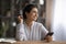 Smiling dreamy Indian woman holding credit card and smartphone