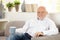 Smiling elderly man having coffee on sofa