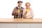 Smiling elderly man and woman holding glasses with orange juice behind a wooden counter