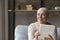 Smiling elderly tablet user sitting on couch in good thoughts