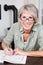 Smiling elderly woman doing a crossword puzzle