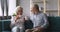 Smiling elderly woman drinking hot coffee with husband at home.