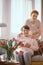 Smiling elderly woman drinking tea with her caregiver in the retirement home