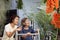 Smiling elderly woman in garden. Happy senior woman and daughter sitting on terrace with red jade vine flowers at home