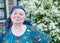 Smiling elderly woman in a kerchief on background of white flowers in your garden