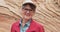 Smiling elderly woman looking at camera in front of rocky sandstone cliff