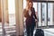 Smiling elegant woman walking with her baggage in airport talking on smartphone