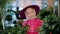 Smiling elegant young girl touching green plants indoors