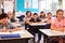 Smiling elementary school kids sitting at desks in classroom