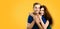 Smiling embracing young couple in love. Orange yellow background. Man and woman. Copy space