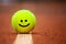 Smiling emoji on tennis ball lies on the clay court