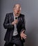 Smiling emotional moving happy performer man presenting the show holding microphone in hand on grey color background. Closeup