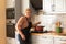 Smiling energetic elderly woman cooking in the kitchen