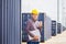 Smiling engineer man with laptop showing thumbs up in the container cargo, Foreman in hardhat and safety vest checking containers