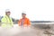 Smiling engineers discussing at construction site on sunny day