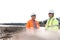 Smiling engineers discussing at construction site on sunny day