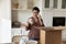 Smiling ethnic female renter unpack parcel with kitchenware