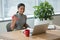 Smiling executive exercising with dumbbells while working laptop