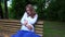 Smiling expectant mother sitting on bench and caress tender her belly in park