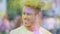 Smiling face of happy young man shaking head covered in colorful dye at festival