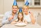 Smiling family in blue hats blowing favor horns