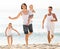Smiling family of four running on sandy beach