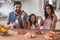 Smiling family looking at the camera and holding cookies with milk glasses in the kitchen