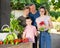 Smiling family standing on backyard with harvested vegetables