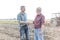 Smiling farmers shaking hands while standing on field at farm