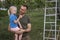 Smiling father holds little daughter in arms in orchard. Family picking apples. Girl eats ripe juicy apple outdoors