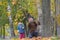 Smiling father with laughing daughter tossing up yellow autumn leaves in park outdoors