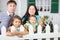 Smiling father, mother, baby and daughter stand next to fence