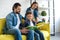 smiling father with two kids reading book together while sitting on couch