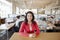 Smiling female architect at a desk in busy open plan office