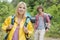 Smiling female backpacker looking away with man standing in background at forest