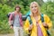 Smiling female backpacker looking away with man standing in background at forest