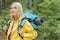 Smiling female backpacker in raincoat looking away at forest