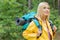 Smiling female backpacker in raincoat looking away at forest