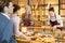 Smiling female bakers in maroon aprons working behind counter