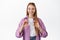 Smiling female bank client, young woman student showing her credit card, looking happy at camera, standing over white