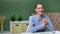 Smiling female blogger sitting at table talking showing gesture cool. Medium shot on RED camera