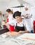 Smiling Female Chef Cutting Ravioli Pasta At