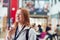 Smiling Female College Student Talking Into Mobile Phone In Busy Communal Campus Building