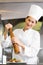 Smiling female cook grinding pepper on food in kitchen