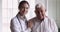 Smiling female doctor embrace happy senior patient look at camera