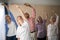 Smiling female doctor and seniors exercising with arms raised