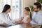 Smiling female doctor using stethoscope, listening to little girl heartbeat