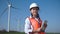 Smiling female engineer standing against wind farm